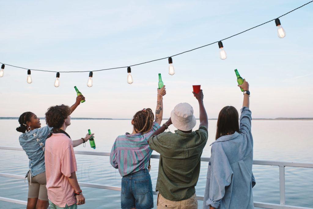 Rear view of young friends with drinks enjoying outdoor party